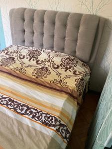 a bed with a gray headboard with a blanket at Cozy spacious apartment in Chişinău