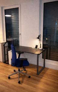 an office with a desk with a blue chair and a laptop at Modern Nature Apartment ! WIFI & Parking Free ! in Frauenfeld