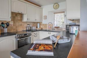 a kitchen with white cabinets and a book on the counter at Tanderra Coniston in Coniston