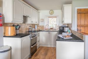 a kitchen with white cabinets and black counter tops at Tanderra Coniston in Coniston +15 photos