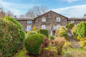 a stone house with bushes in front of it at Tanderra Coniston in Coniston