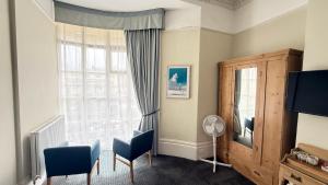 a living room with a large window and blue chairs at Brighton House in Brighton & Hove