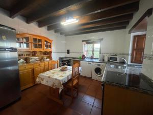 a kitchen with a table and a sink and a dishwasher at Casa Rural La Xana in Piloña +89 photos