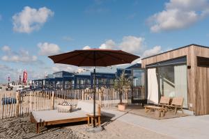 a patio with a table and an umbrella at Piatti beach suites in Zandvoort