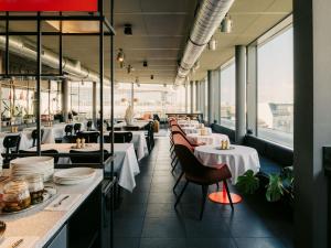 a restaurant with white tables and chairs and windows at Casa Camper Berlin in Berlin