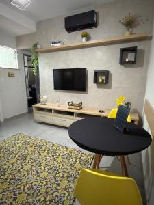 a living room with a table and a tv on a wall at Apartamento Completo localizado no centro in Matias Barbosa +2 photos