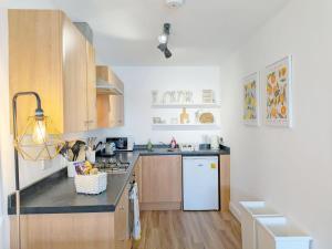 a kitchen with wooden cabinets and a white refrigerator at The Beach Flat - Selsey in Selsey