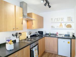 a kitchen with wooden cabinets and a stove top oven at The Beach Flat - Selsey in Selsey +8 photos
