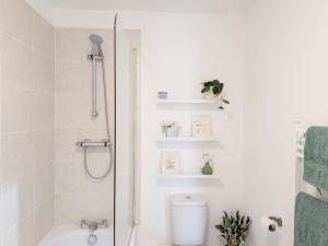 a white bathroom with a shower and a toilet at The Beach Flat - Selsey in Selsey