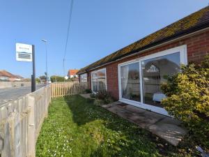 a brick house with a window on the side of a street at The Beach Flat - Selsey in Selsey