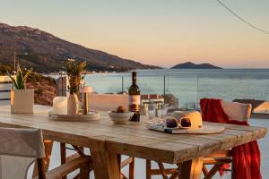 a wooden table with a bottle of wine and glasses at Villa Alexia - Private Pool & Panoramic Sea Views in Órmos Koumaíïkon