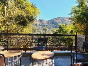 a patio with tables and chairs with mountains in the background at Perth villa in Mount Ābu