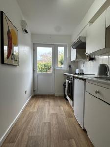 a kitchen with white cabinets and a large window at The Garden Haven in Cheddar