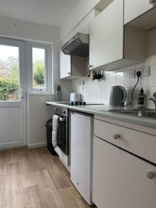 a kitchen with white cabinets and a sink at The Garden Haven in Cheddar