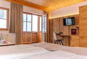 a bedroom with a bed and a desk and a tv at Hotel Langeck in Maria Alm am Steinernen Meer