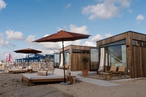 a pavilion with chairs and an umbrella on the beach at Piatti beach suites in Zandvoort