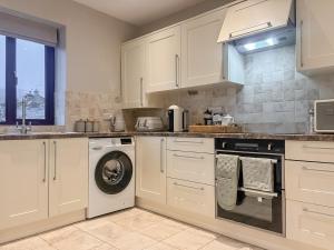 a kitchen with white cabinets and a washing machine at The Coach House in Kettlewell