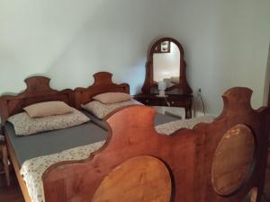 a bedroom with two wooden beds and a mirror at Fótos Vendégház in Tiszaderzs