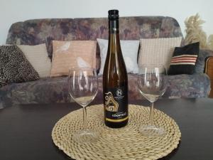 a bottle of wine and two wine glasses on a table at Fótos Vendégház in Tiszaderzs