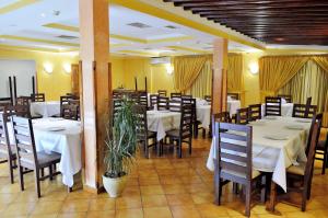 una sala da pranzo con tavoli e sedie bianchi e una pianta di Hotel Alrawabi a Nefza