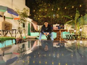 a man sitting in a chair next to a pool at Art Bliss Rishikesh - Yoga Hostel & Café in Rishīkesh