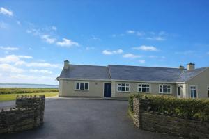 a house with a stone fence in front of it at Cliff Top Accommodation in Spanish Point