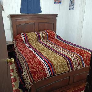 a bed with a quilt on it in a room at Hostal Adriana in Valdivia +1 photo