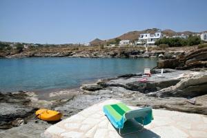 a chair sitting on the rocks near the water at Beachfront Majestic Villa in Liaropá +67 photos