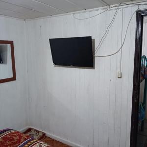 a tv on a white wall in a room at Hostal Adriana in Valdivia