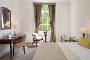 a hotel room with a bed and a desk and a window at Taplow House Hotel & Spa in Maidenhead