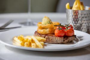 a white plate with a piece of steak and french fries at Taplow House Hotel & Spa in Maidenhead