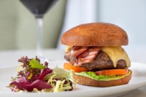 a hamburger with cheese and bacon and a salad on a plate at Taplow House Hotel & Spa in Maidenhead