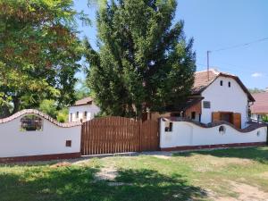 a fence in front of a white house at Fótos Vendégház in Tiszaderzs