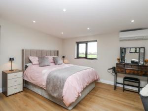 a bedroom with a bed and a dresser and a mirror at Aloe Lodge in Diss