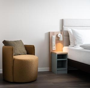 a bedroom with a chair next to a bed at elaya hotel oberhausen, Trademark by Wyndham in Oberhausen +37 photos