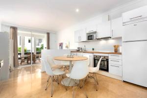a white kitchen with a table and white chairs at Fuente de la Duquesa in Manilva