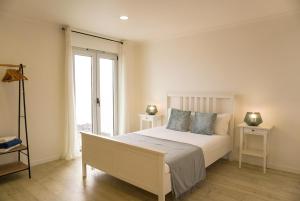 a bedroom with a white bed and a window at South Shore 1 - Jacuzzi - HOST & CHILL in São Roque