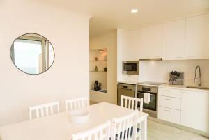 a kitchen with white cabinets and a white table and chairs at South Shore 1 - Jacuzzi - HOST & CHILL in São Roque