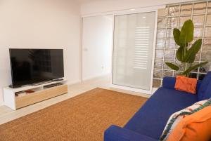 a living room with a blue couch and a tv at South Shore 1 - Jacuzzi - HOST & CHILL in São Roque