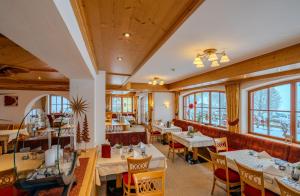 a restaurant with tables and chairs and windows at Hotel Langeck in Maria Alm am Steinernen Meer