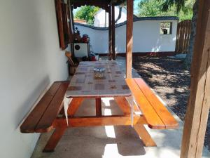 a wooden picnic table sitting outside of a house at Fótos Vendégház in Tiszaderzs