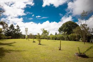 a field with trees and a water tower in the distance at Véio Chico’s Ranch | Swimming Pool | Barbecue in Ibiúna