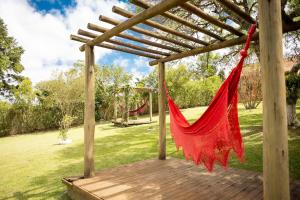 a red hammock hanging from a wooden pergola at Véio Chico’s Ranch | Swimming Pool | Barbecue in Ibiúna