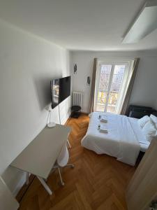 a bedroom with a bed and a desk and a television at Cosy studio a Lausanne center in Ouchy