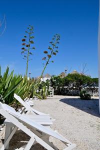 two white lounge chairs sitting on the beach at Windmill of Mykonos in Mikonos