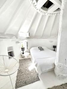 a white bedroom with a bed and a table at Windmill of Mykonos in Mikonos