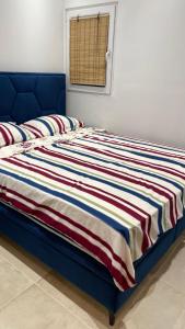 a blue bed with a striped blanket on it at Apartmani PARADISO in Čapljina
