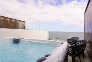 a hot tub on a balcony with the ocean in the background at South Shore 2 - Jacuzzi - HOST & CHILL in São Roque