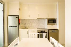 a kitchen with white cabinets and a table and a refrigerator at South Shore 2 - Jacuzzi - HOST & CHILL in São Roque