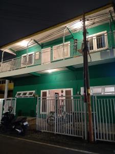 a green building with a balcony and a motorcycle parked in front at Edotel Tebe Syariah in Rampal +22 photos